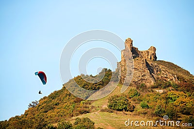 A man flies in his paraglider near Siria Medieval Fortress in Arad County, Romania. Stock Photo