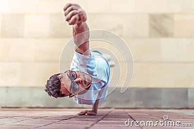 Man in flight, stands on one arm, Superman pose, young guy dancer, in summer in city, dancing street dances, modern Stock Photo