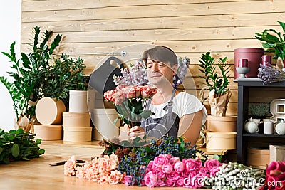 Man florist assistant in flower shop delivery make rose bouquet Stock Photo