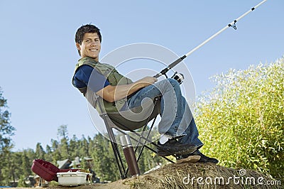 Man fly fishing, sitting on collapsible chair Stock Photo