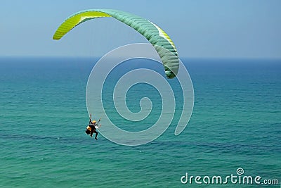 Man is flying on green paraglider in the sky above the azure sea. Balance, extreme sports, lifestyle. Mediterranean Sea Israel Stock Photo
