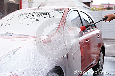 Man foaming red auto at car wash. Stock Photo