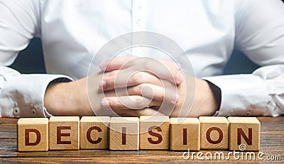 Man folded his hands on a background of blocks with the word Decision. Make the right decision, the answer to the question Stock Photo