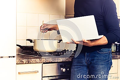 Man following recipe on his laptop computer Stock Photo