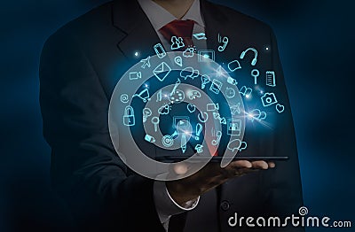 A man in formal suit is holding a tablet with flying out hologram social media icons. Stock Photo
