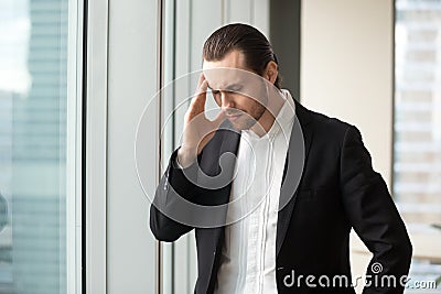 Man in formal wear standing with eyes closed touching temples Stock Photo