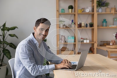 Man freelancer sit at desk with laptop staring at camera Stock Photo