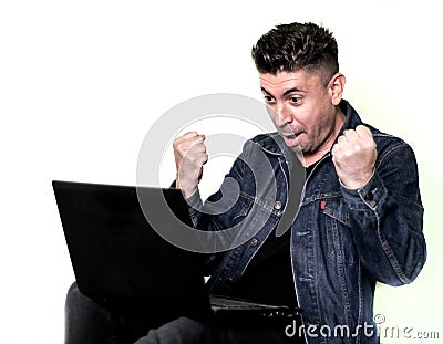 Man in front of laptop. He looks very excited and happy at the laptop screen. The man is very happy with the results Stock Photo