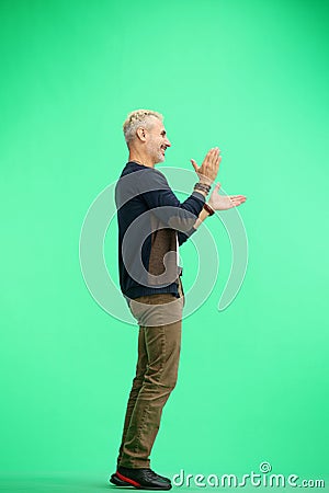 A man, full-length, on a green background, claps Stock Photo