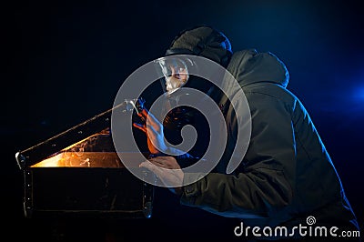 The man in the gas mask opens an old suitcase Stock Photo