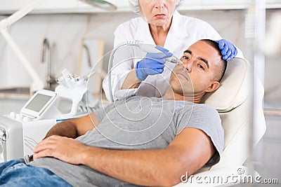 Man getting facial deep hydration procedure from experienced cosmetologist in aesthetic medicine clinic Stock Photo