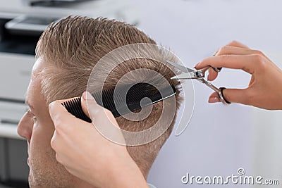 Man Getting Haircut From Hairdresser At Salon Stock Photo