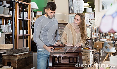 Man with girlfriend admiring vintage wooden bureau Stock Photo