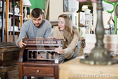 Man with girlfriend admiring vintage wooden bureau Stock Photo