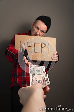 Man gives alms to the homeless. unemployed takes money for a living. cardboard begging. vertical shot Stock Photo