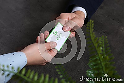 Man giving medical business card to woman on dark background. Nephrology service Stock Photo