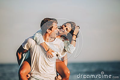 Man giving piggyback ride to girlfriend on beach Stock Photo