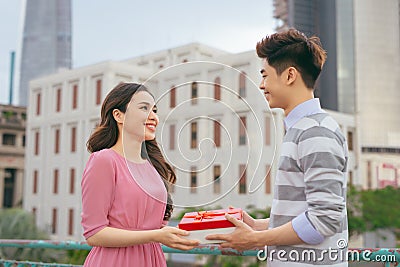 Man giving to his woman a gift. Asian couple in love outdoors Stock Photo