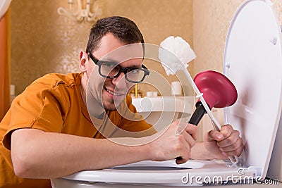 Man in glasses cleaning the toilet bowl Stock Photo