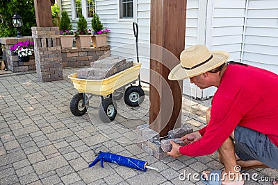 Man gluing bricks to form a pillar on a patio Stock Photo