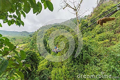 man going on zipline adventure through the forest in Lao Stock Photo