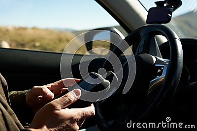 A man with a GPS navigator in his hands inside a car in the mountains. Excerpt. Stock Photo