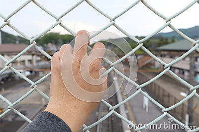 Man grasp the bar of cage with the defocus of city background Stock Photo