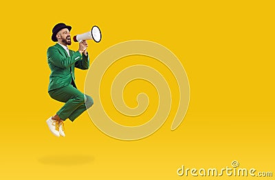 Man in green suit shouts into loudspeaker announcing crazy discounts for St. Patrick's Day. Stock Photo