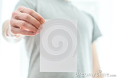 Man in a grey t-shirt holding a blank white piece of paper Stock Photo