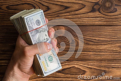 Man gripping a thick stack of 100 dollar bills Stock Photo