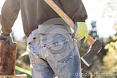 Man in grunge blue jeans chopping wood Stock Photo