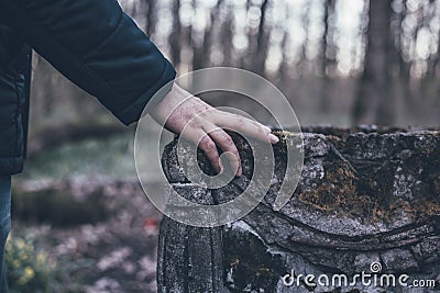 Man hand on ancient tombstone covered with moss, sorrow and eternal memory for dead people concept Stock Photo