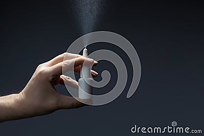 Man hand with a bottle of medication for runny nose during grippe on dark background. Treatment colds via a nasal spray Stock Photo