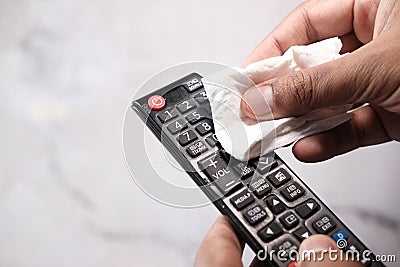 Man hand cleaning TV remote controller with disinfectant wet wipe Stock Photo