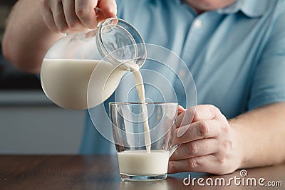 Man hand flowing milk from jar into glass Stock Photo