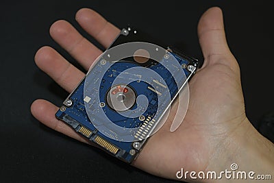 Man hand hold an hdd memory storage device over dark surface,tech components,data security parts Stock Photo