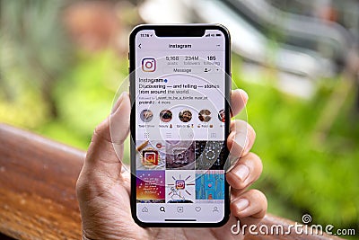 Man hand holding iPhone X with social networking service Instagram Editorial Stock Photo