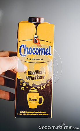 Man hand holding yellow pack of Chocomel chocolate drink against gray background Hallo Winter edition - Dutch dirnk Editorial Stock Photo