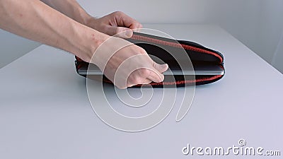 Man hand putting laptop into a case, zipping it up and taking away of the table. Action. Close up of male hand placing Stock Photo