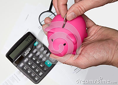 Man hand putting money to piggy bank - Stock image Stock Photo