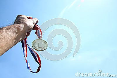 Man hand raised, holding gold medal against skyl. award and victory concept. selective focus. retro style image. Stock Photo