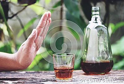 Man hand rejecting glass with alcoholic beverage on table outdoors background - refuses to drink a alcohol whiskey Stock Photo