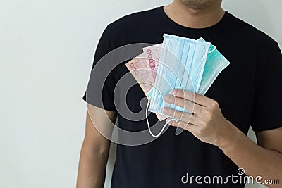 Man hand`s holding medical protective mask and cash thai bath. Concept mask expensive Stock Photo