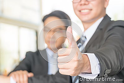 Man hand showing thumbs up on the foreground. Businessman showing OK sign with his thumb up. Selective focus on hand Stock Photo