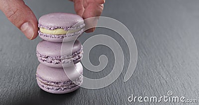 Man hand stacking lavender macarons on slate board Stock Photo