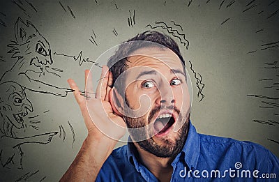 Man with hand to ear gesture and evil voices screaming blaming him Stock Photo