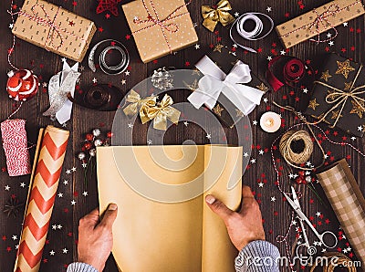 Man hand unfolding roll of wrapping kraft paper for packing christmas gift box Stock Photo