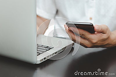 Man hand using smart phoneand laptop on table at home, searching information browsing the internet on web, work from home. Stock Photo