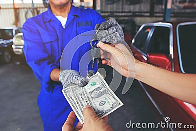 Man handed the money to Car mechanic holding in a hand car keys Stock Photo