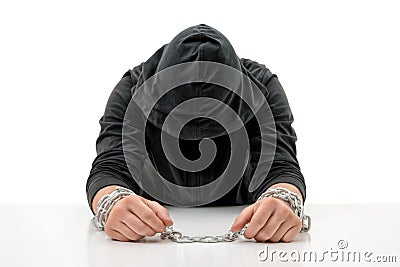 Man with hands in chains is sitting head bowed. Stock Photo